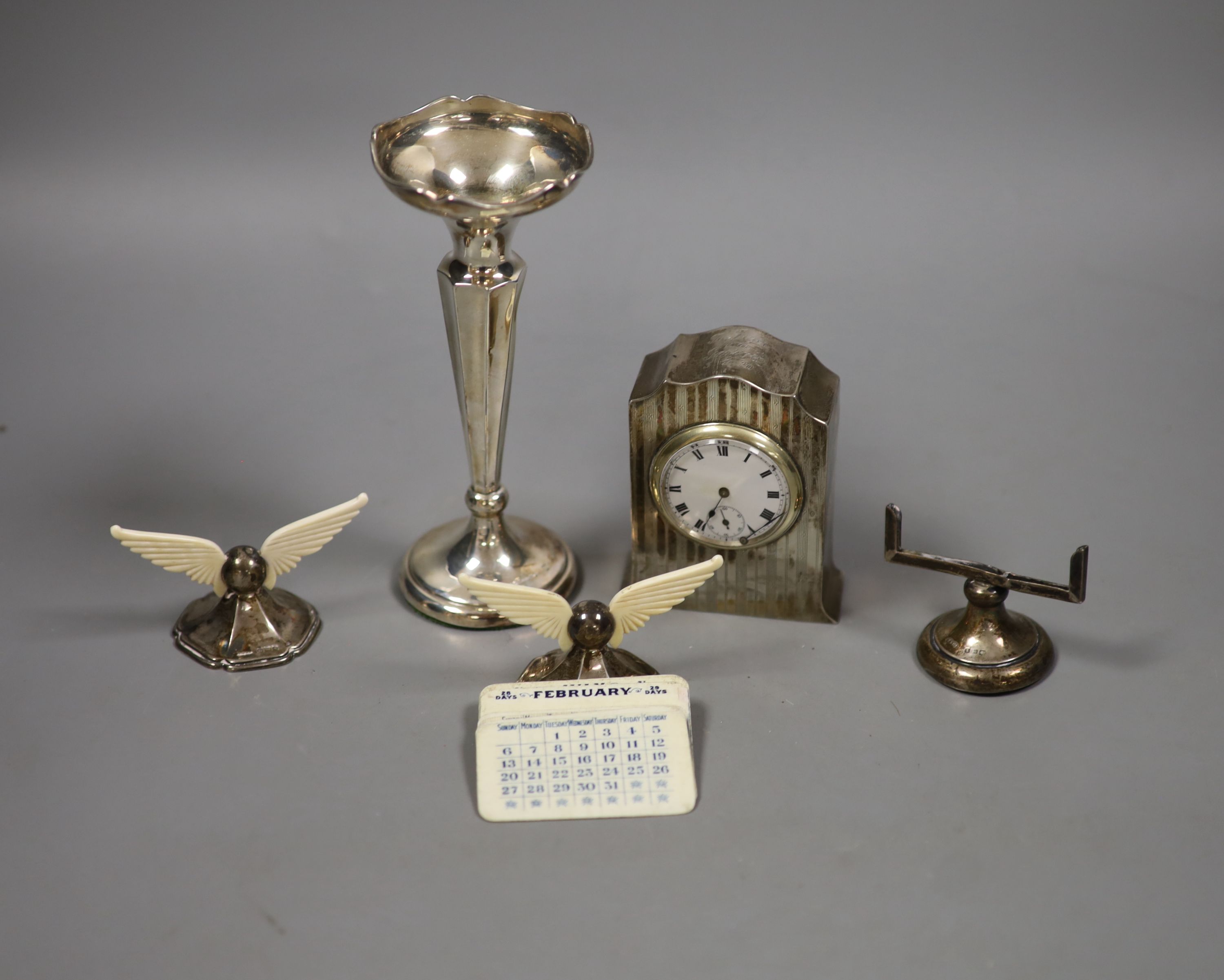 A George V silver cased bedside timepiece, a silver and ivory perpetual calendar and a pair of silver and ivory knife rests